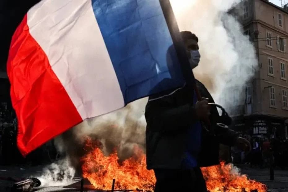 Un manifestante sostiene una bandera francesa junto a un incendio durante enfrentamientos en Marsella, en el sur de Francia (17.10.2026).