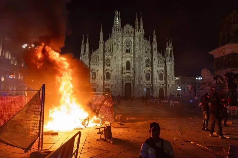 Una fogata arde en la plaza frente a la catedral de Milán tras los choques entre policías y manifestantes.