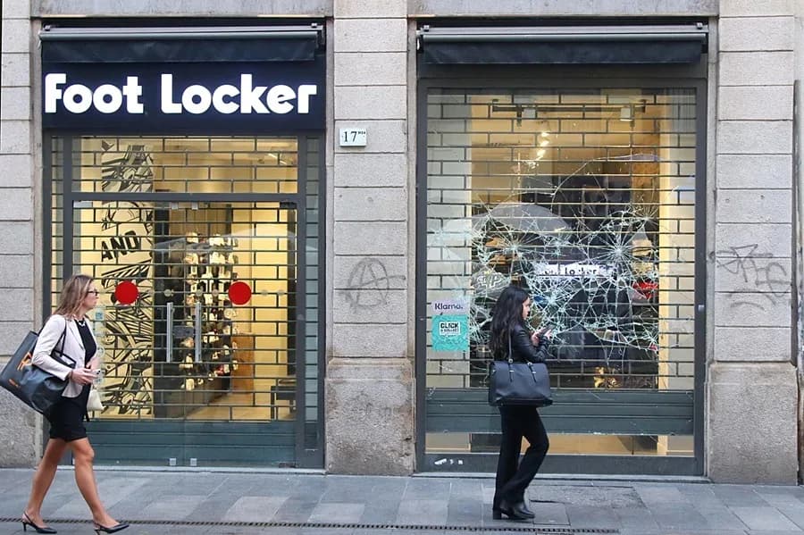 La gente pasa junto al escaparate destrozado de una tienda tras dos días de disturbios protagonizados por jóvenes, en Milán, Italia.