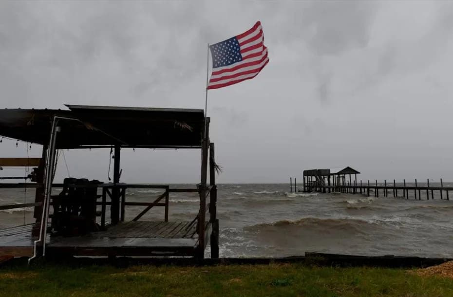Una bandera estadounidense ondea al viento provocado por los efectos del huracán Isaías en una playa vacía en Mon Louis Island, Alabama.