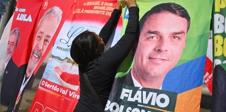 Un mujer organiza en una tienda informal, banderas con la imagen del presidente de Brasil y candidato a la reelección, Luiz Inácio Lula da Silva y del candidato presidencial, Flávio Bolsonaro.
